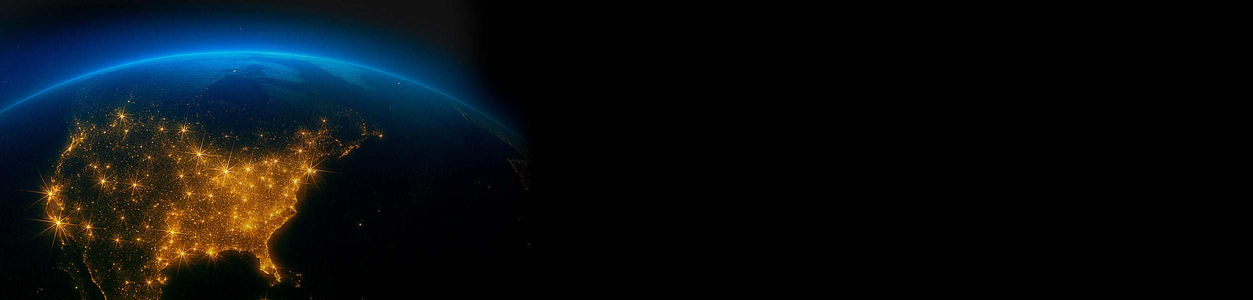 Earth at night with illuminated cities, viewed from space.